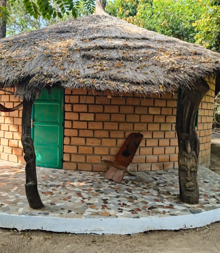 habitación en edificio tradicional senegales redondo con techo de paja y hamaca para descansar en la puerta